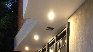 Fachada de un edificio con un patio adoquinado, rejas de metal y un muro de hormigón.
