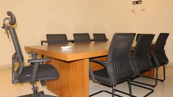A conference room with a wooden table and six black office chairs.