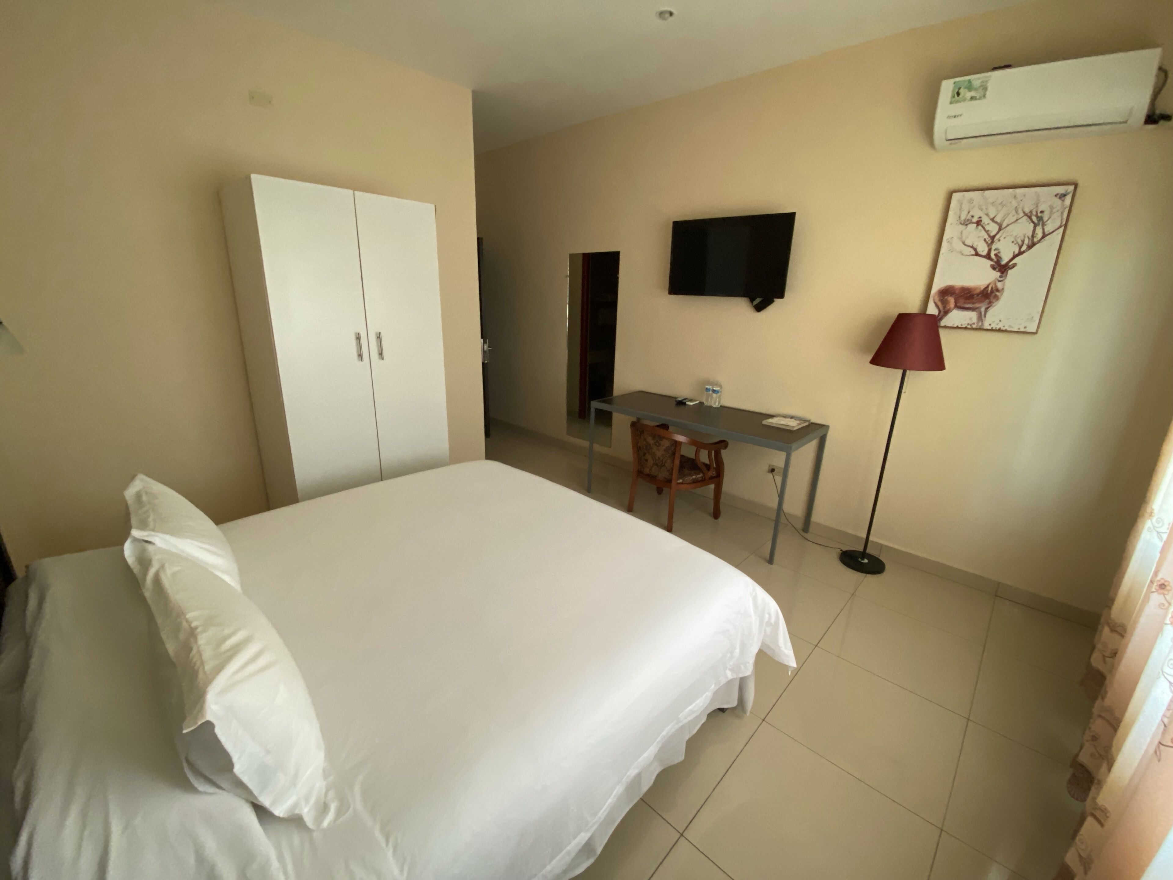 Ein Hotelzimmer mit einem Bett, einem Schreibtisch, einem Sessel, einem Fernseher und einem Kleiderschrank.