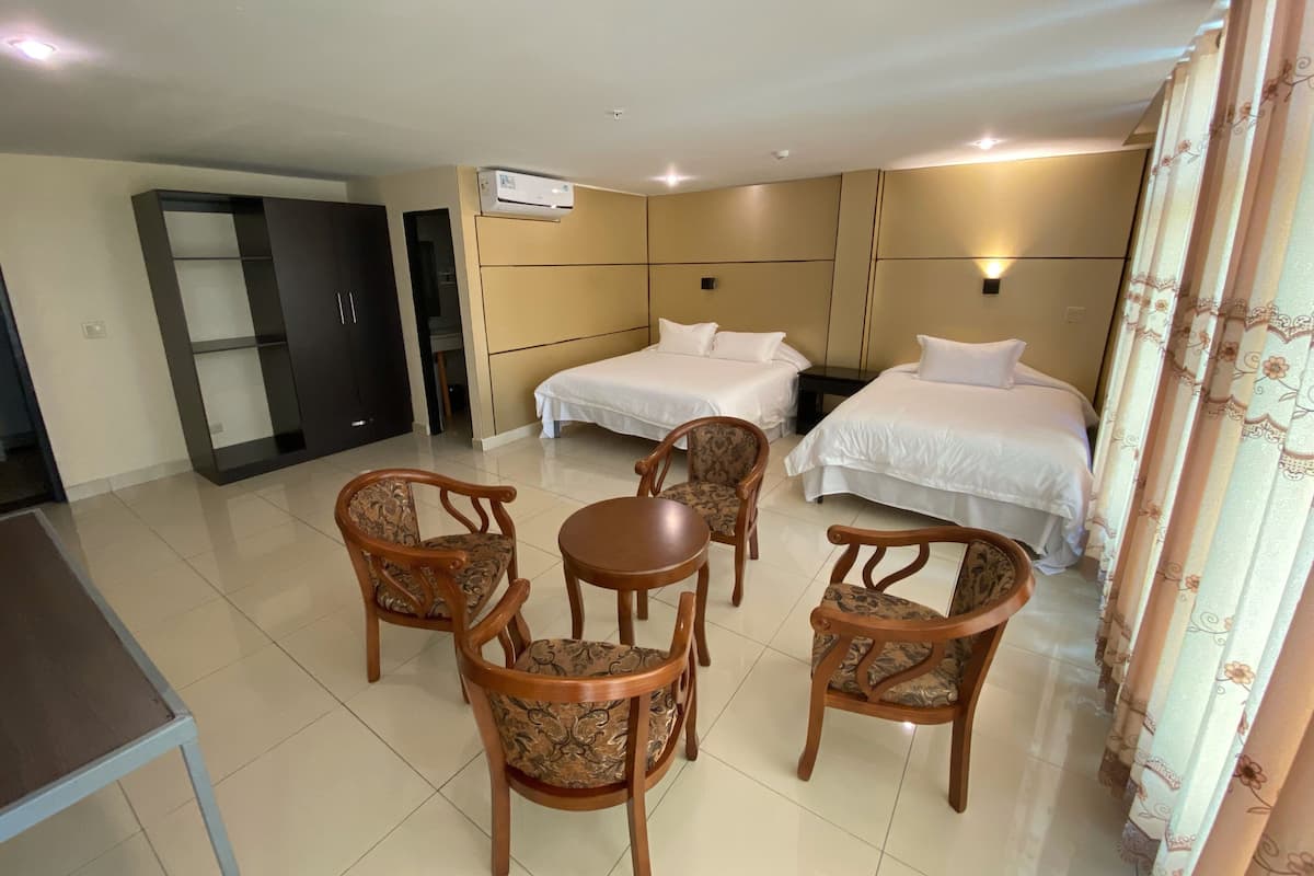 A hotel room with two beds, a desk, and four chairs.