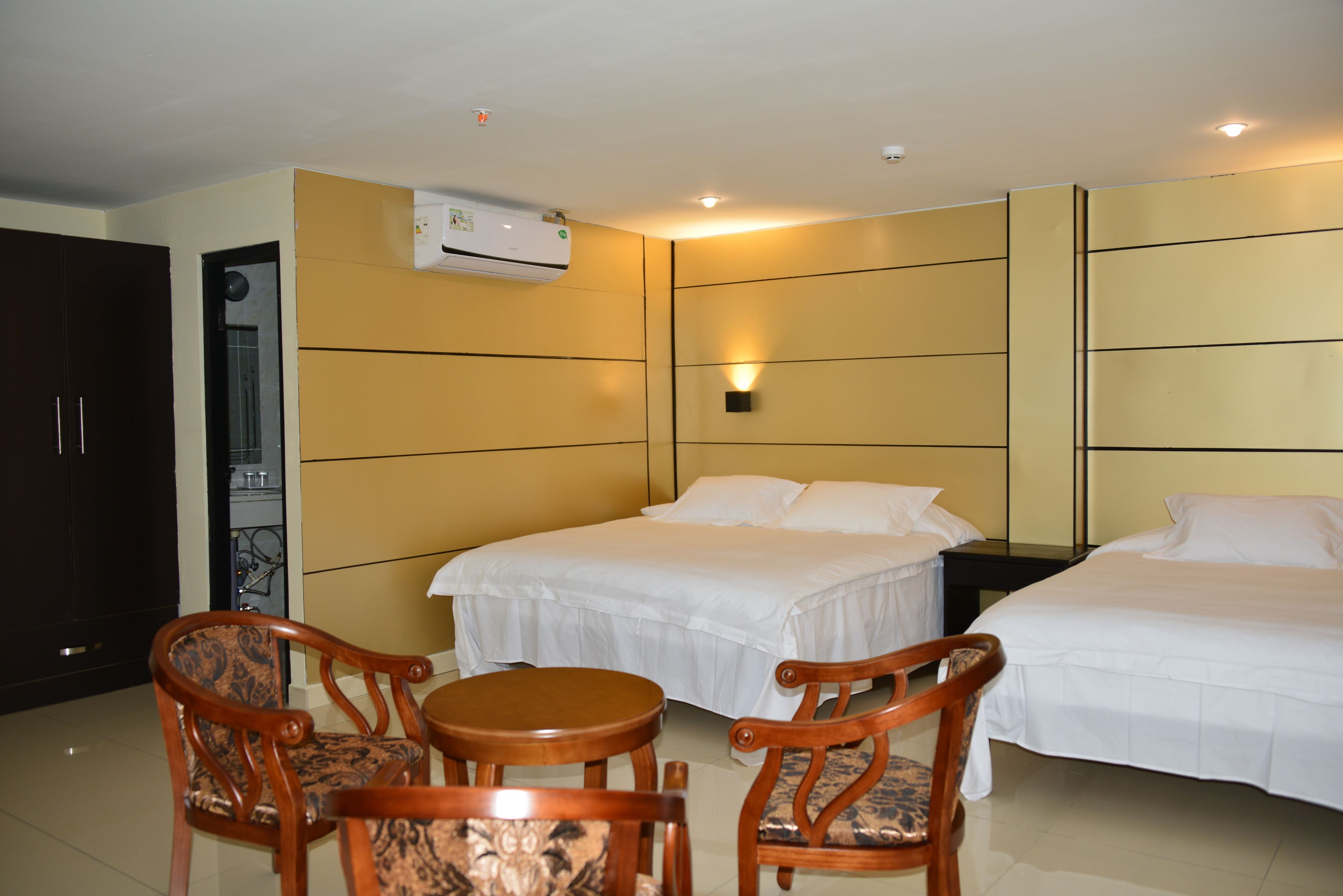 A hotel room with two beds, a dining table, and two chairs.