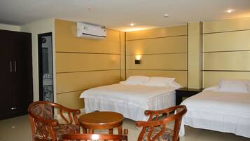 A hotel room with two beds, a dining table, and two chairs.