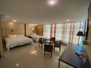 A hotel room with two beds, a dining table, and chairs.