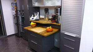 Una cocina compacta con refrigerador, cafetera y un tazón de fruta en la encimera.