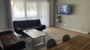 A modern living room with a sofa, coffee table, and TV mounted on the wall. - Family friendly, free wifi, exclusive amenities, (Rheinhausen (Breisgau))