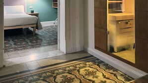 Una habitación de hotel con una cama, una mesita de noche, una alfombra estampada y un armario de madera con puerta de cristal.
