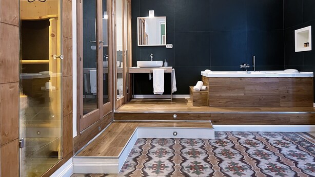 Un baño moderno con tocador de madera, un espejo grande y una bañera.