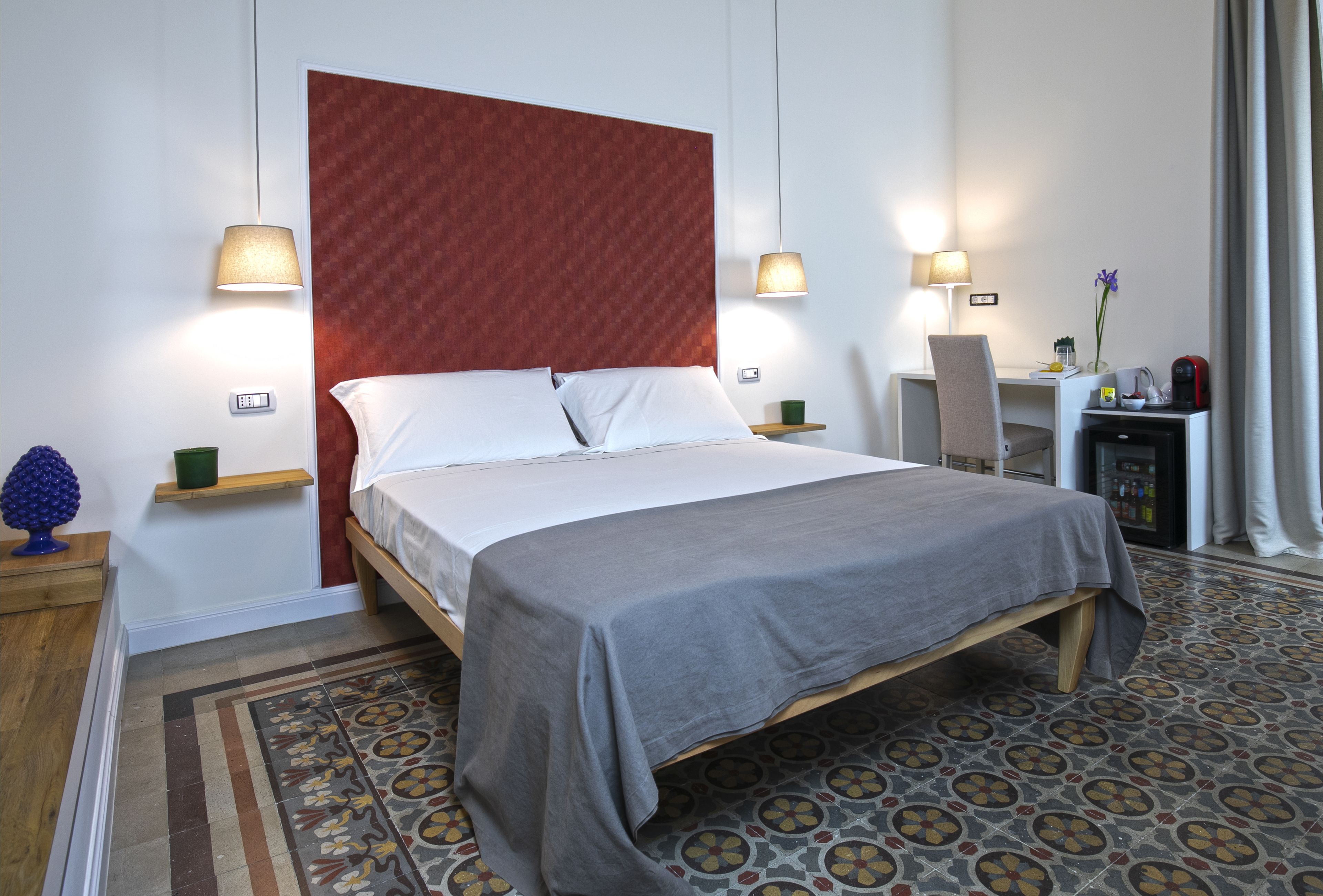A hotel room with a bed, bedside tables, a desk, and a chair.