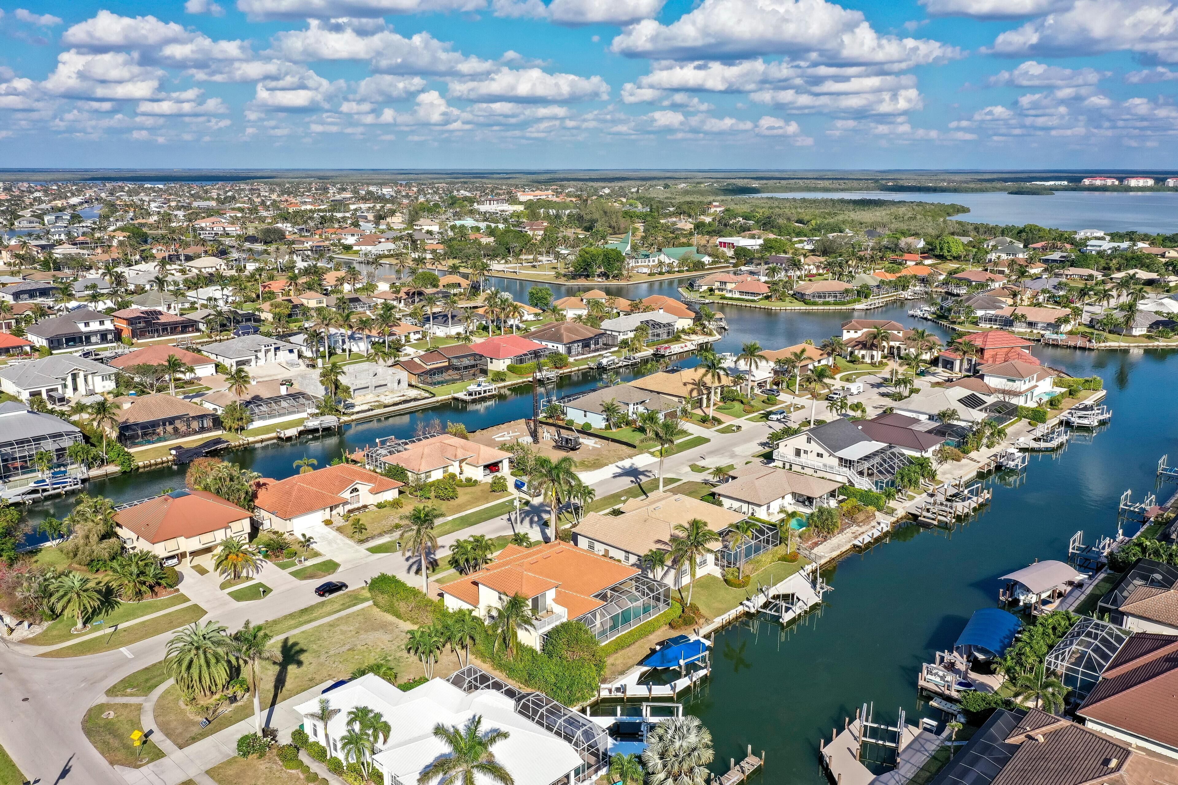 Vue aérienne d’un quartier résidentiel avec des maisons, un port de plaisance et une étendue d’eau.