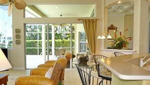 A spacious dining area with wicker furniture, a bar counter, and a view of the outdoors. - 931 Hyacinth Court (Marco Island)