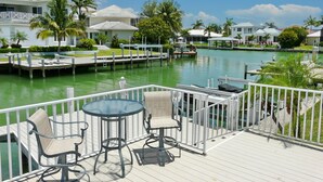 A waterfront deck with outdoor seating and a view of the marina. - 931 Hyacinth Court (Marco Island)