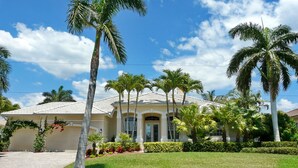 A two-story house with a tiled roof, surrounded by palm trees and a well-maintained lawn. - 931 Hyacinth Court (Marco Island)