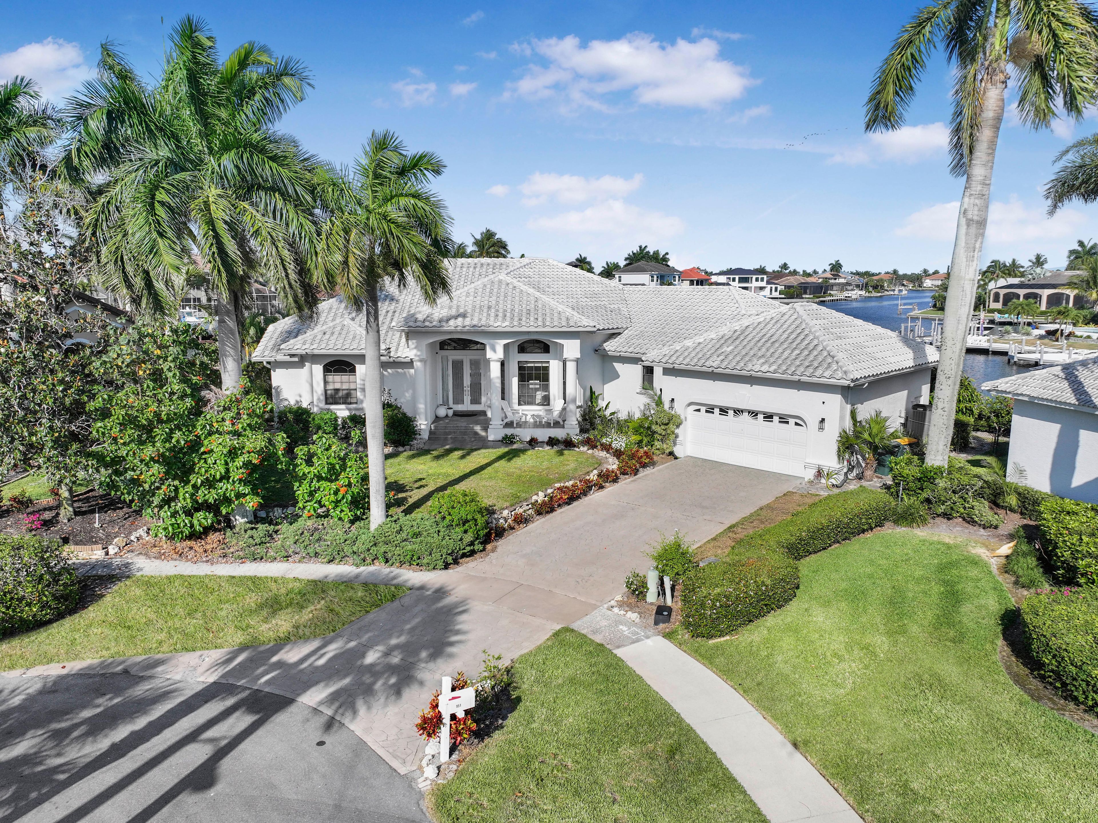 A residential house with a driveway, a lawn, and a palm tree.