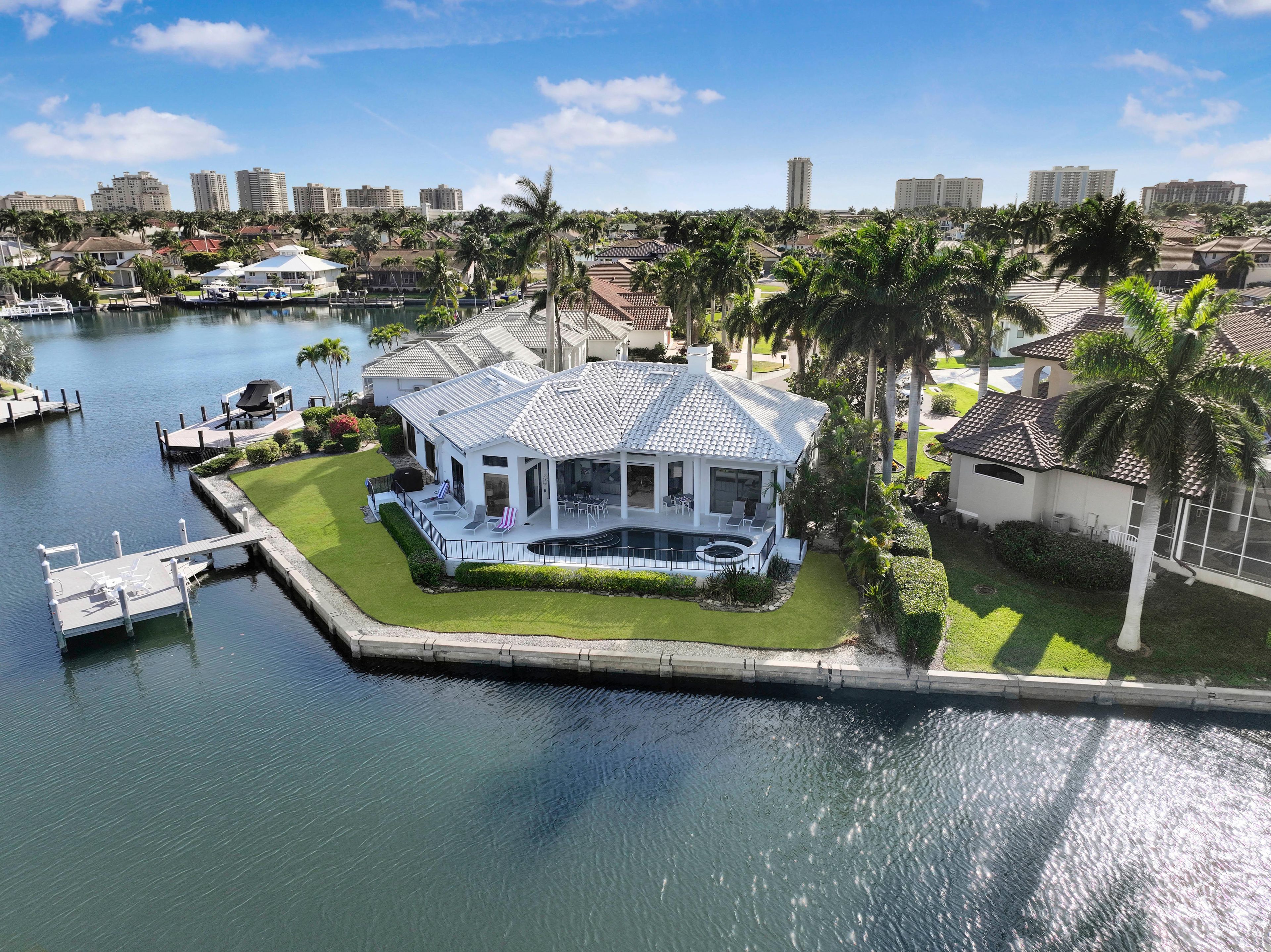 A waterfront property with a covered patio, a swimming pool, and a dock.