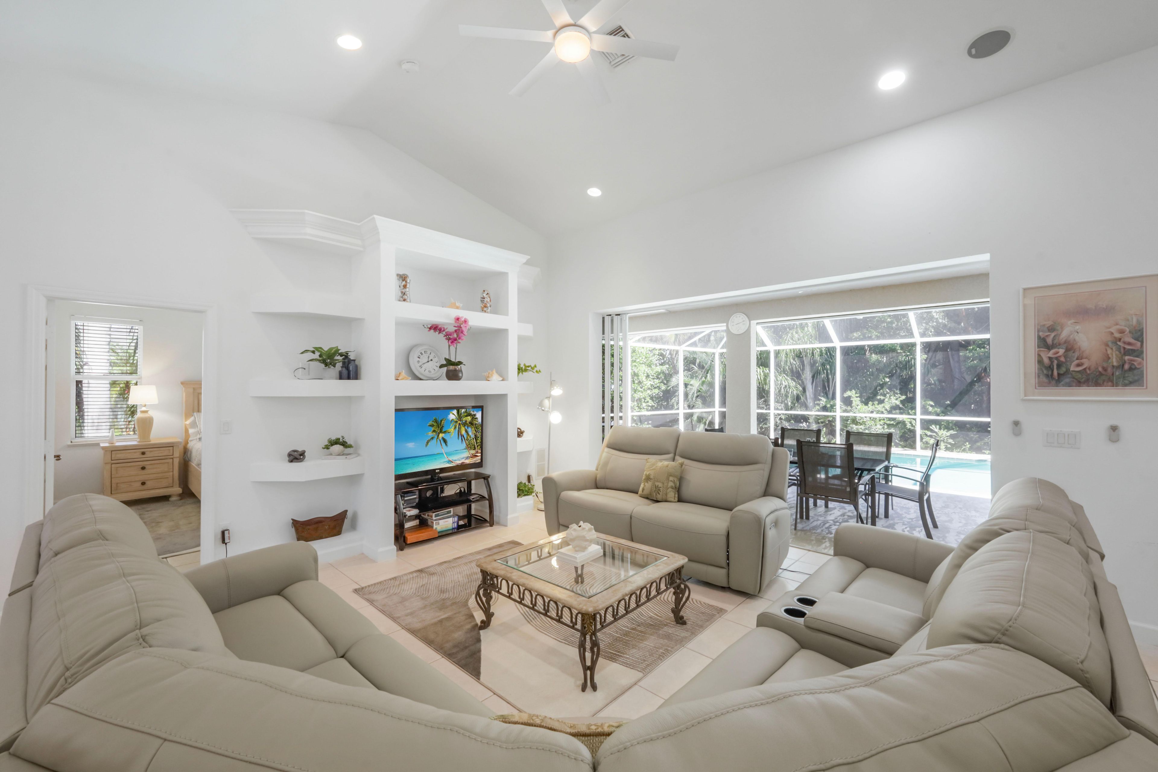 A spacious living room with a flat-screen TV, two sofas, a coffee table, and a dining area with a view of the outdoors.