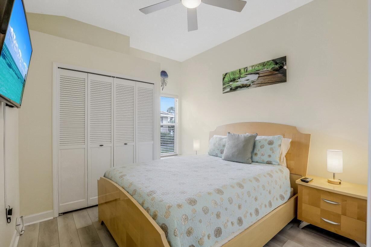 A bedroom with a bed, bedside table, nightstand, and a painting on the wall.