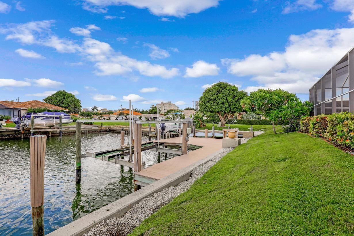 A marina with docked boats, a grassy area, and a modern building.