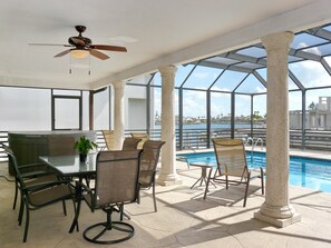 An outdoor patio with a pool, seating, and a ceiling fan. - 987 Aster Court (Marco Island)