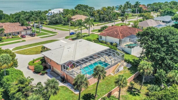 Un quartier résidentiel avec une grande maison dotée d’une piscine couverte et offrant une vue sur un lac.
