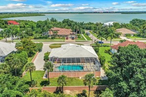 A residential area with a large swimming pool, surrounded by lush greenery and a view of a lake. - 550 Inlet Drive (Marco Island)