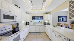 Une cuisine moderne avec des meubles blancs, un four à micro-ondes, une cuisinière et un évier.