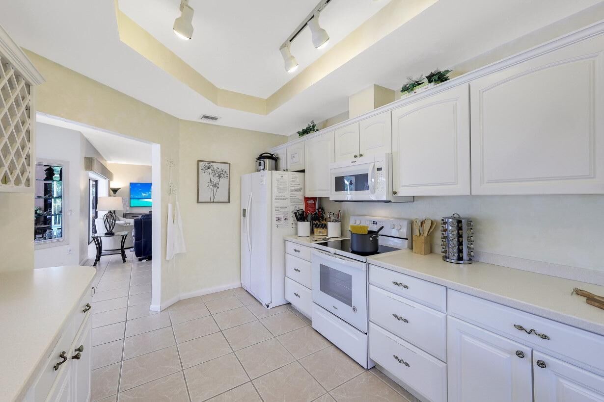 A modern kitchen with white cabinetry, a microwave, stove, and a refrigerator.