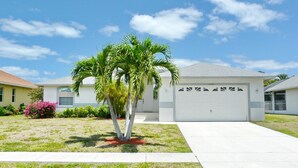 A residential house with a garage, a lawn, and a palm tree. - 1292 Bayport Avenue (Marco Island)