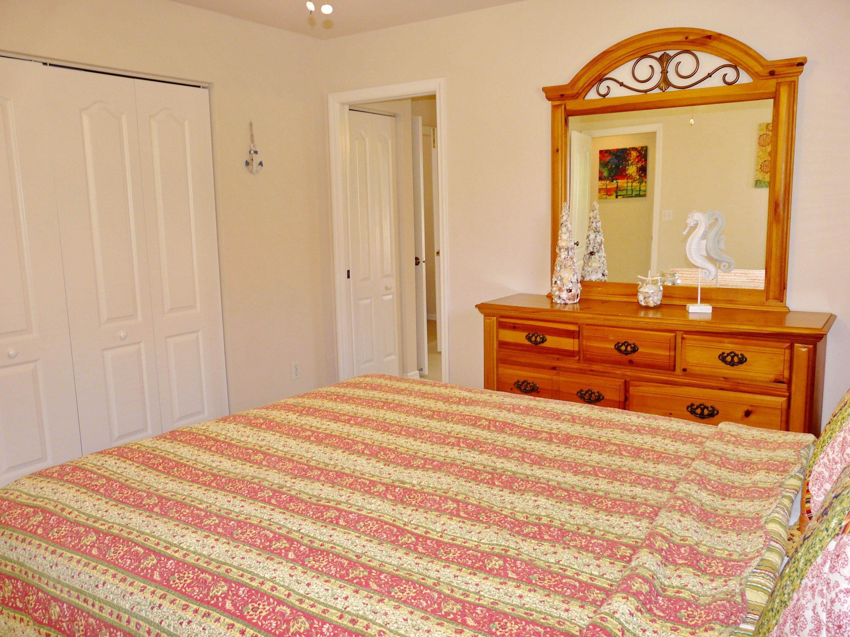 Un dormitorio con cama, cómoda y espejo.