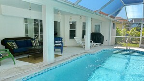 An indoor swimming pool with a covered patio area, including seating and a grill. - 1292 Bayport Avenue (Marco Island)