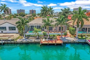 A resort with a pool, palm trees, and a city skyline in the background.