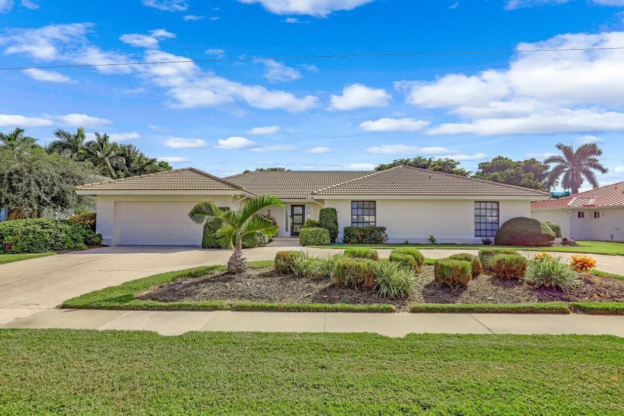 A two-story house with a tiled roof, a front garage, and a well-maintained lawn with various plants.