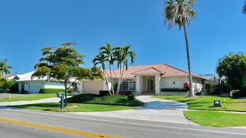 A single-story house with a red-tiled roof, a front driveway, and a well-maintained lawn.