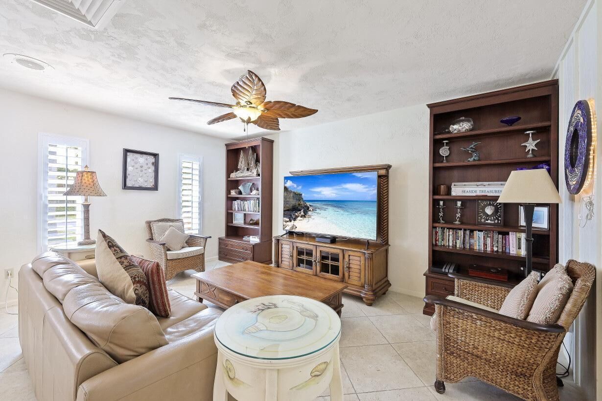 A living room with a sofa, coffee table, bookshelf, and a television displaying a beach scene.