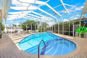 Indendørs swimmingpool med et gennemsigtigt glasloft, omgivet af liggestole og et murstensgulv.