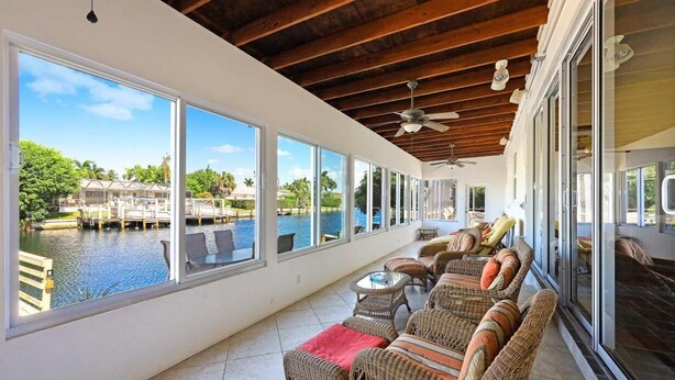 A covered outdoor seating area with wicker furniture and a view of a water body. - 775 Willow Court (Marco Island)
