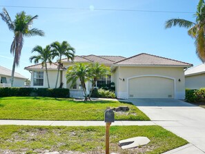 A residential house with a tiled roof, a garage, and a well-maintained lawn with palm trees. - 779 Amazon Court (Marco Island)