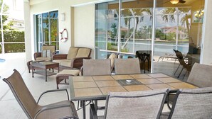 A sunlit patio with wicker furniture, a pool view, and a ceiling fan. - 1684 Rainbow Court (Marco Island)