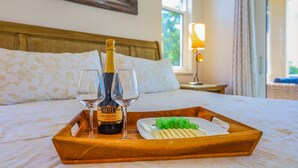 A bed with a wooden headboard, a bottle of Ariel Brut Cuvée wine, two glasses, and a tray with cheese and grapes. - Waterfront Home With Pool, spa and Walk to Beach (Marco Island)