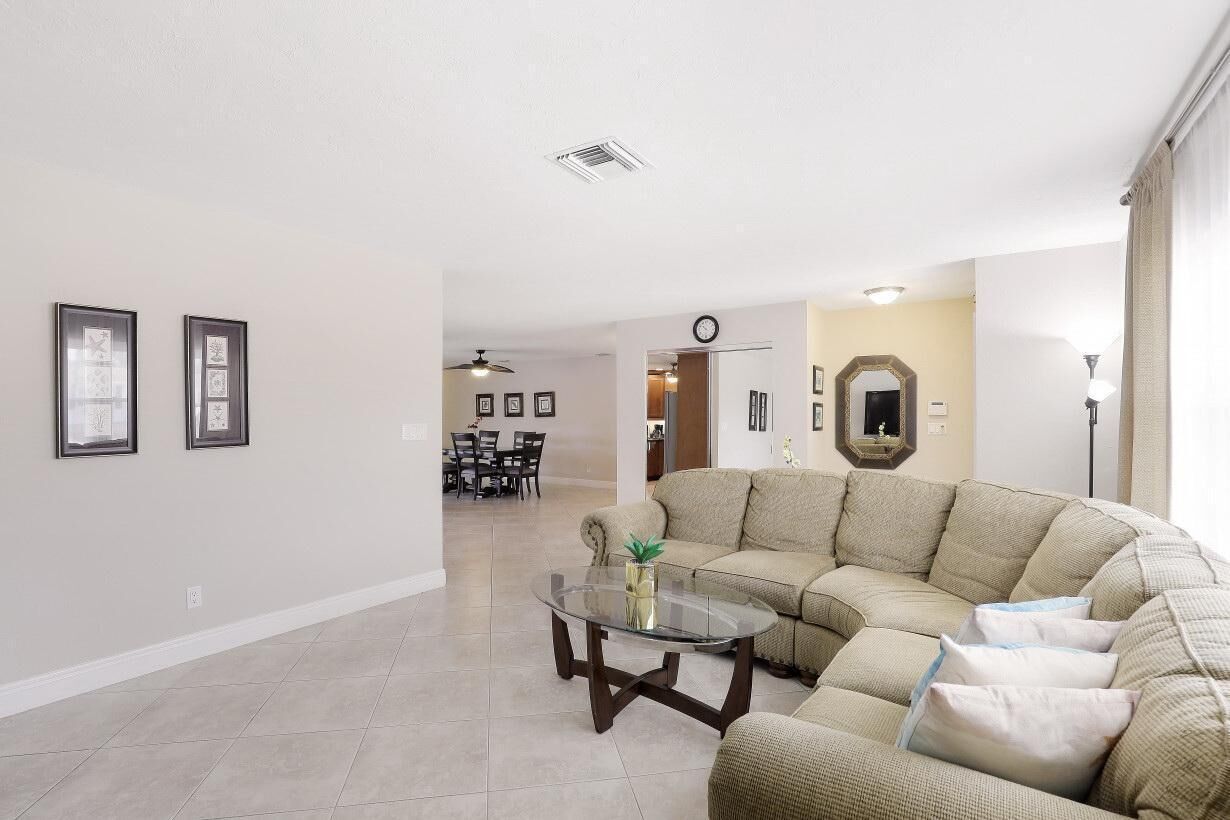 A spacious living room with a sectional sofa, a glass coffee table, and a dining area in the background.