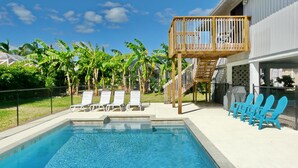 A swimming pool with lounge chairs, a wooden deck, and a covered grill area. - West-facing Home With Pool and 2nd Floor Porch (Marco Island)