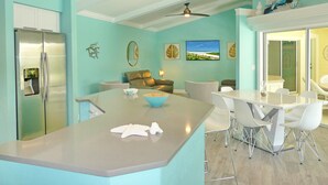 A modern kitchen with a central island, a refrigerator, and a ceiling fan. - Private Home and Guesthouse With Courtyard, Pool and spa (Marco Island)