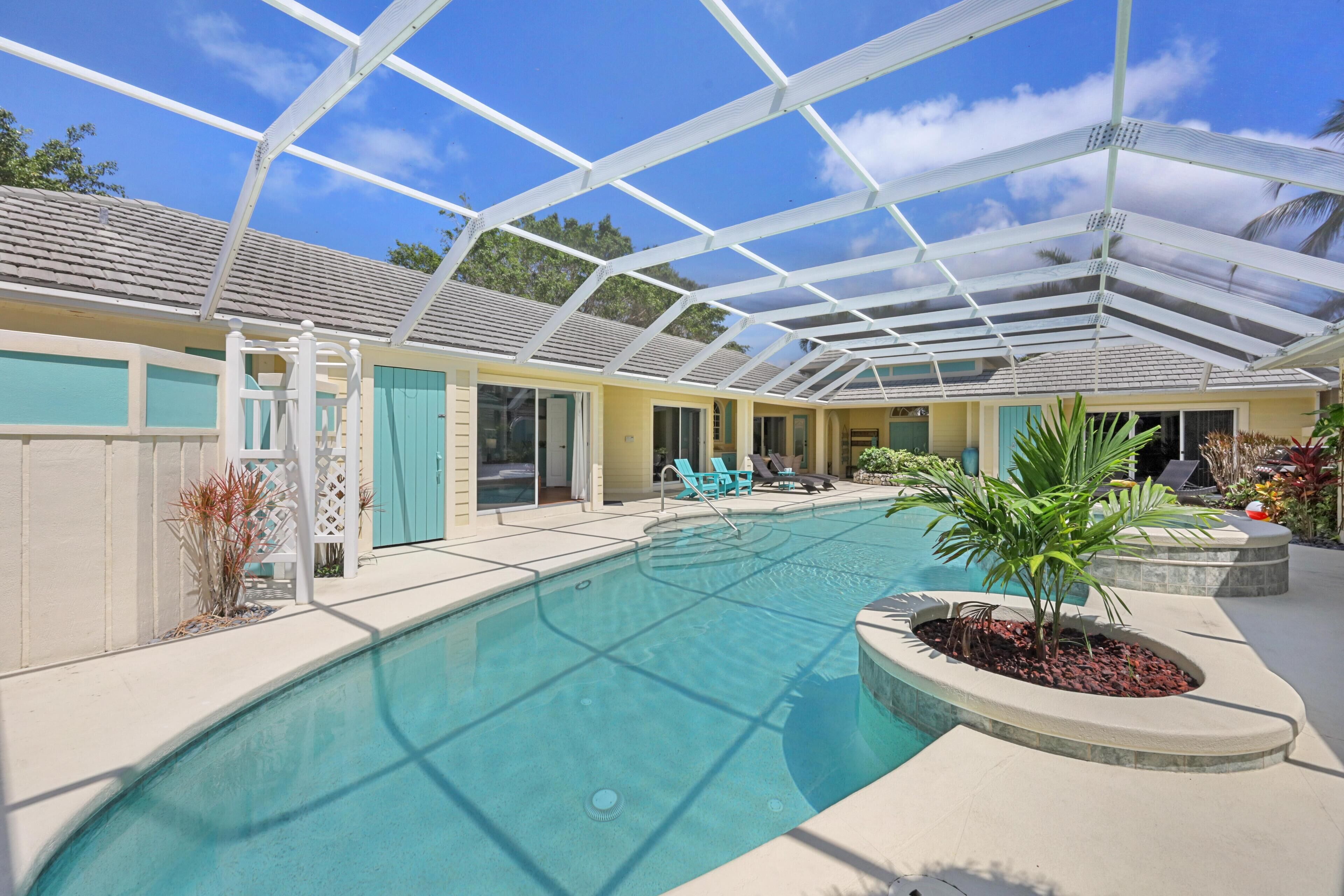 Ein überdachter Pool mit Glasdach, umgeben von Liegestühlen und einer kleinen Gartenanlage.