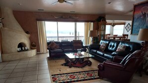 A living room with a black leather sofa, a glass coffee table, and a patterned rug. - Exceptional Lake Powell View Home, lots of parking! (Page)