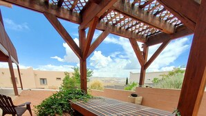 An outdoor patio with a wooden table and benches, surrounded by gravel and potted plants. - Exceptional Lake Powell View Home, lots of parking! (Page)
