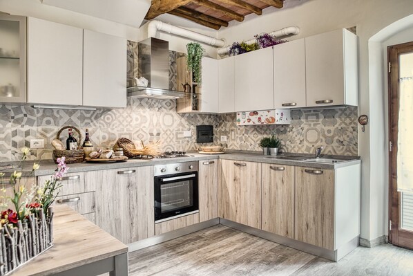 Una cocina moderna con armarios de madera, horno empotrado y encimera con diversos objetos.