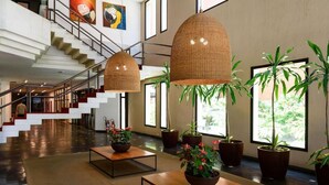 Un vestíbulo amplio con una escalera, ventanas grandes y plantas en macetas.