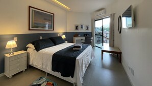 Una habitación de hotel moderna con cama, mesita de noche, lámpara, obras de arte y un balcón con vistas.