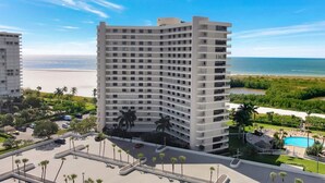 A high-rise hotel with multiple balconies, a swimming pool, and a view of the beach and ocean. - Sun-bright Beachfront Condo With Pool/tennis Courts (Marco Island)