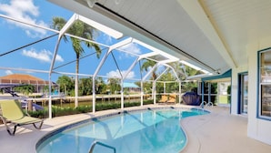 Uma área de piscina com vista desimpedida para a água, um espaço de estar coberto e vista para a paisagem ao redor.
