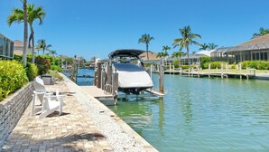 Marina com um barco atracado, cercada por palmeiras e um céu azul límpido.